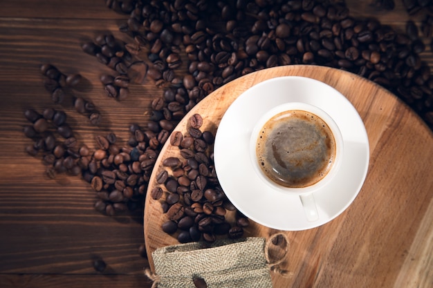 Cup of coffee with coffee beans on the wooden background