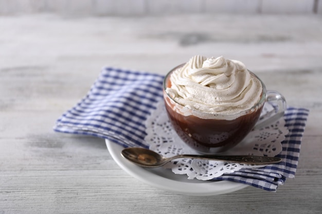 Cup of coffee with cream on color wooden background