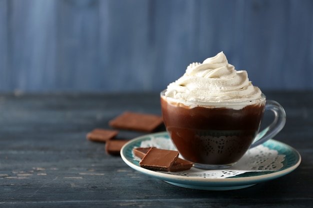 Cup of coffee with cream on color wooden background