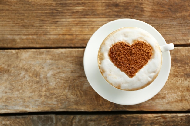 Cup of coffee with creative pattern on wooden table