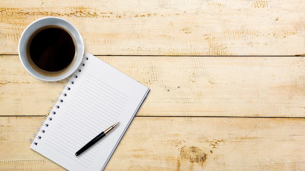 Cup of coffee with an empty book on wooden background International coffee day concept