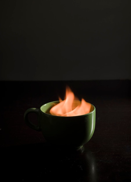 cup of coffee with fire inside, black background