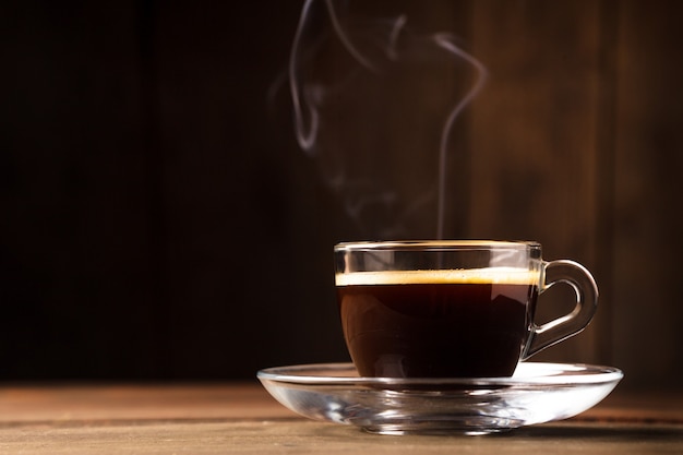 Cup of coffee with fume on the wooden background