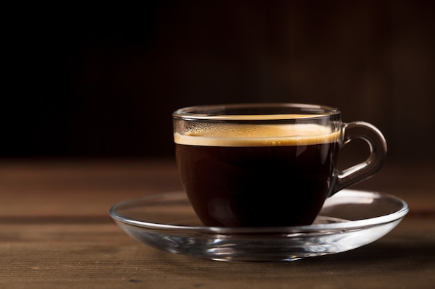 Cup of coffee with fume on the wooden background