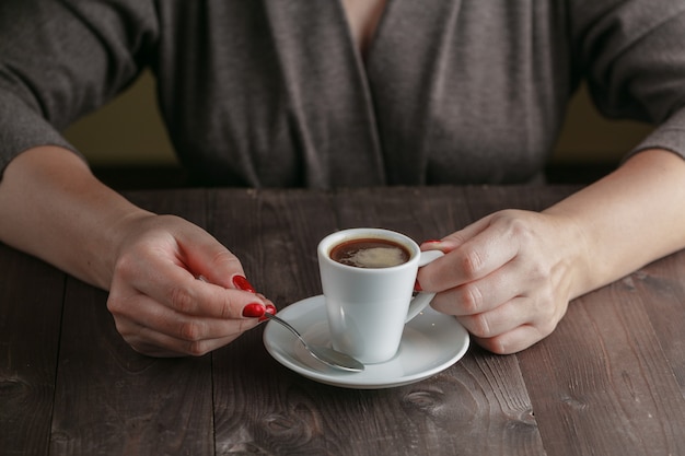 Cup of coffee with hands on wooden table