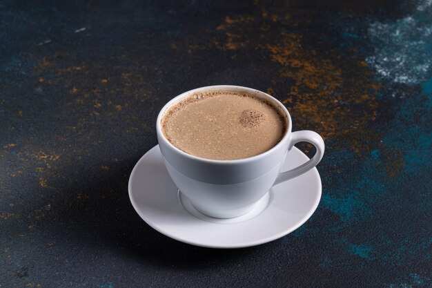 cup of coffee with milk on blue table, top view.