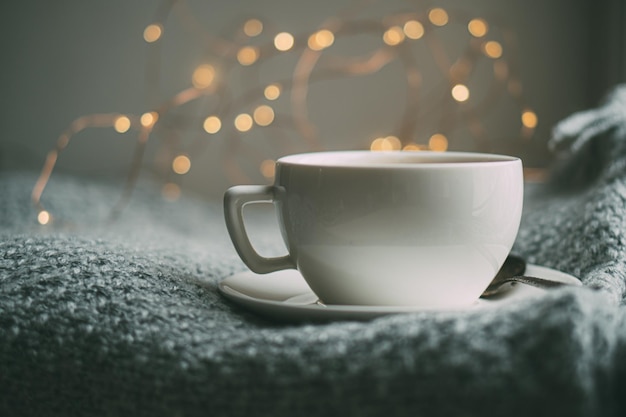 Cup of coffee with milk on cozy knitted winter blanket