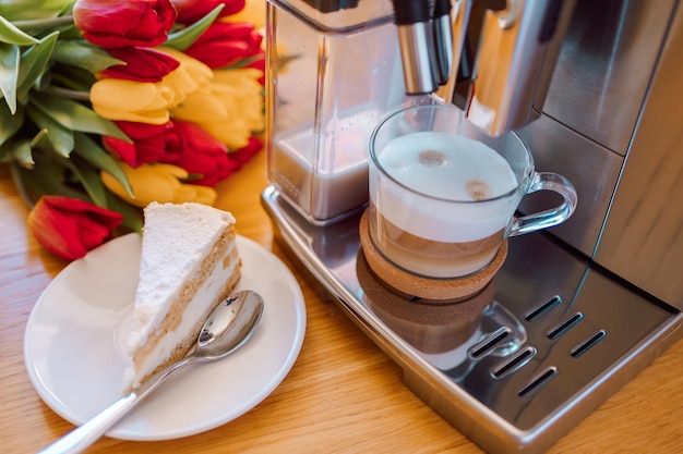 Cup of coffee with milk piece of cake and tulips