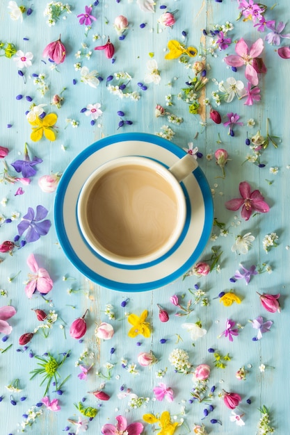 Cup of coffee with milk on a wooden background with small flowers good morning top view