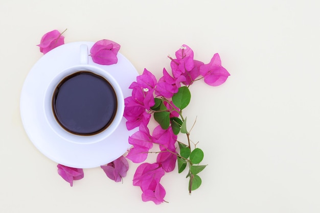 A cup of coffee with a pink flower on the table