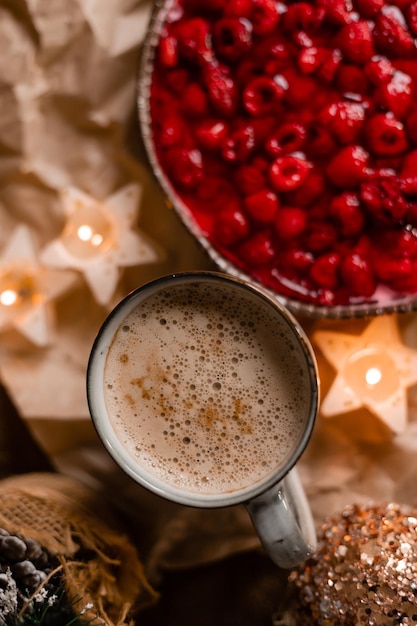 A cup of coffee with a red cranberry sauce in the background