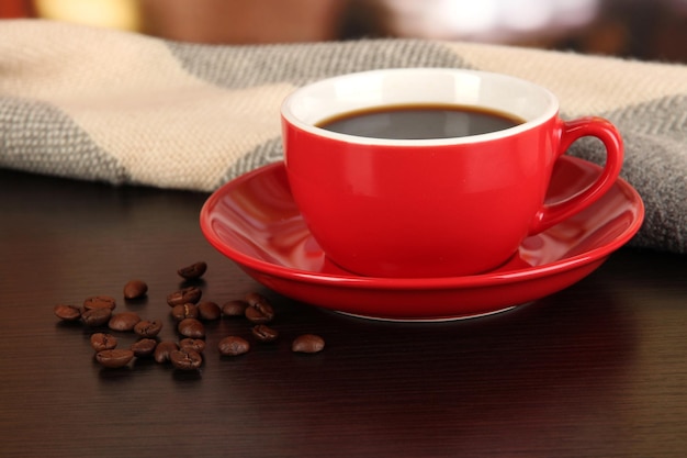 Cup of coffee with scarf on table in room