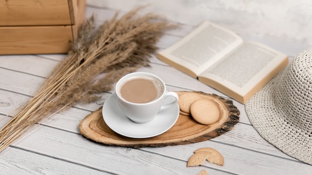 A cup of coffee on wooden slice with cookies and book. Flat lay.