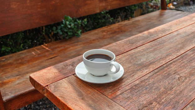 Cup of coffee on wooden table in morning sun