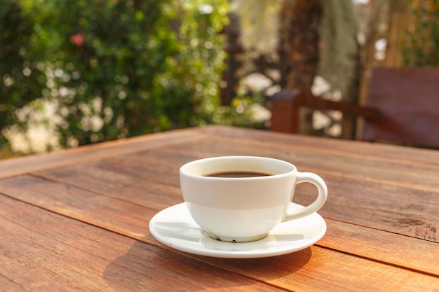 Cup of coffee on wooden table in morning sun