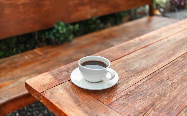 Cup of coffee on wooden table in morning sun