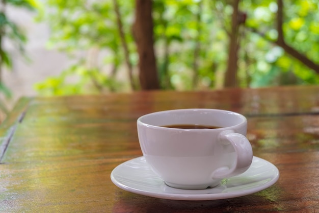 A cup of coffee on a wooden table in the morning with the late morning sunlight.A cup of coffee on a wooden table in the morning with the late morning sunlight.