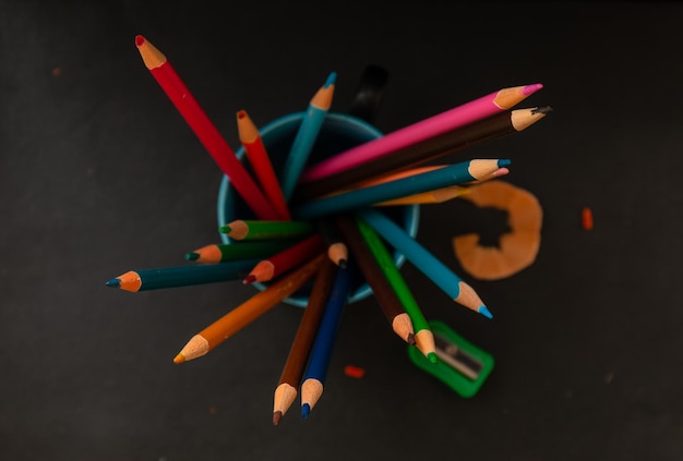 A cup of colored pencils sits on a black table.