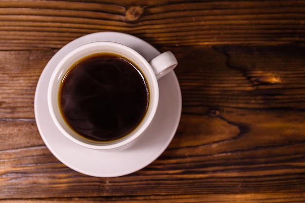 Cup of dark coffee on rustic wooden table. Top view