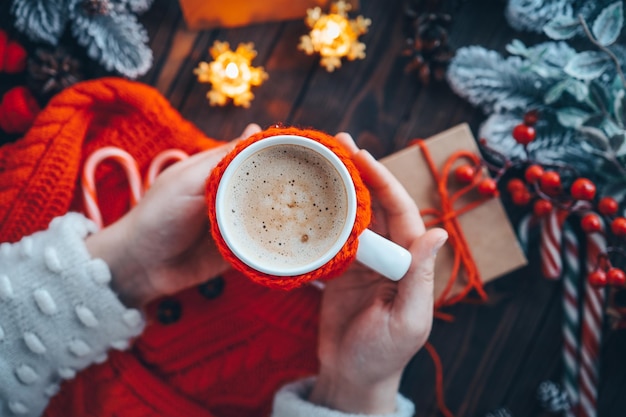 A cup of delicious cocoa in hands against the backdrop of a Christmas atmosphere home comfort