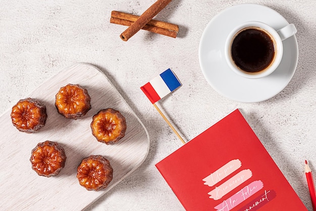 A cup of espresso coffee local French dessert canele red notebook and a French flag