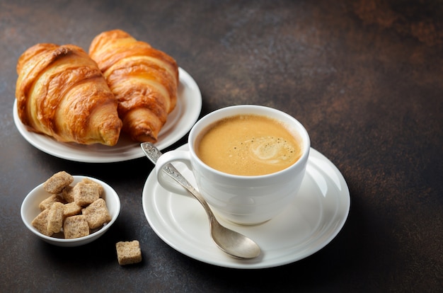 Cup of fresh coffee with croissants.