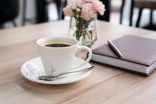 Cup of fresh coffee with notebook and pen on the table Business meeting in a cafe Closeup S