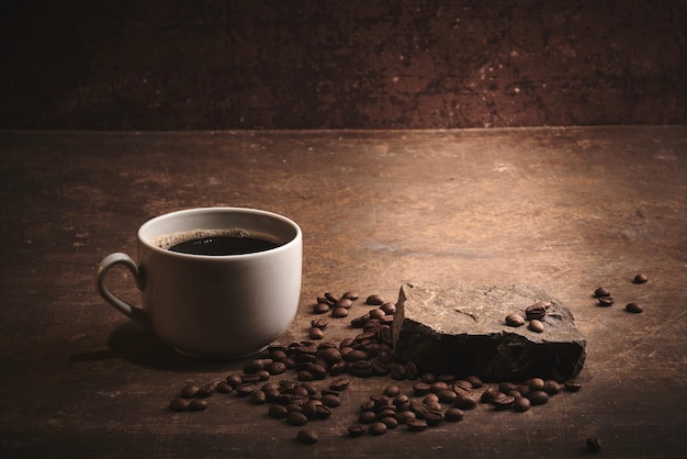 Cup of freshly brewed roasted coffee beans on brown background