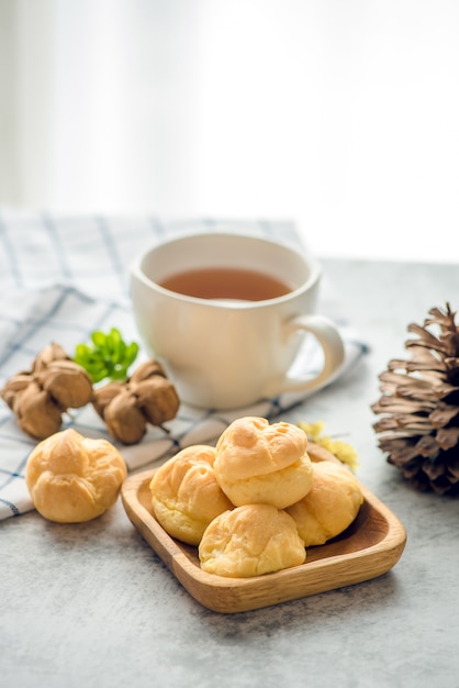 A Cup of freshly brewed tea Inchi peanut,escaping steam,warm soft light, with Eclair sweet on the table