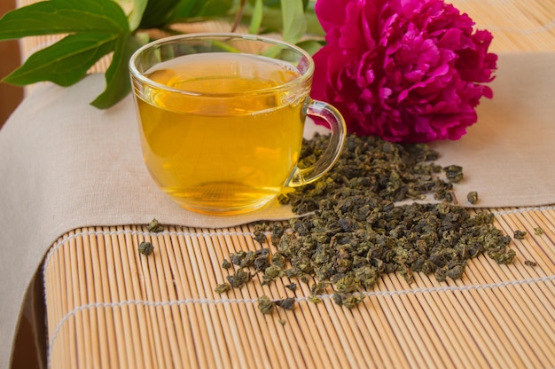 Cup of green tea the leaves loose and peony flower