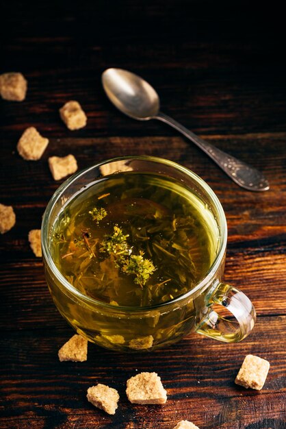 Cup of green tea with brown tea sugar on a wooden background