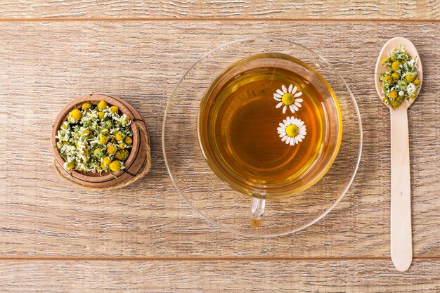 Cup of green tea with chamomile flowers and wooden barrel with dry flowers of chamomile.