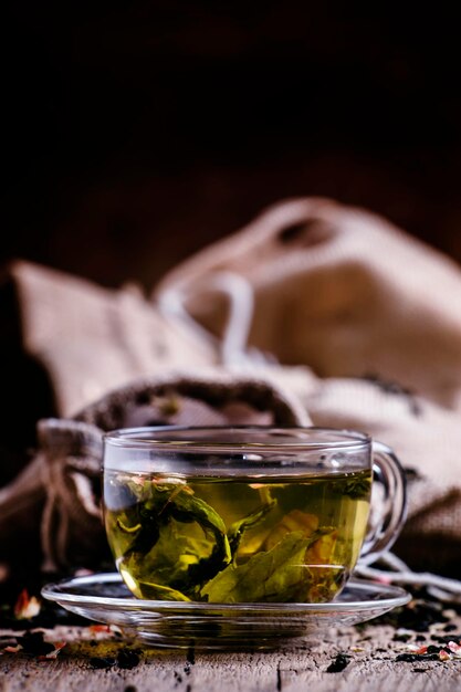 Cup of green tea with flower petals and fruits vintage wooden background selective focus