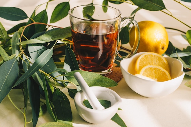 Cup of herbal tea lemon and eucalyptus leaves in small white ceramic mortar