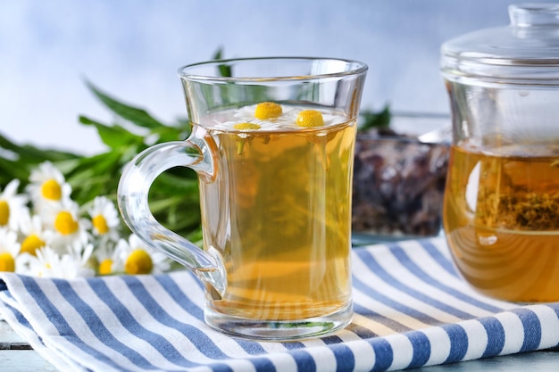 Cup of herbal tea with chamomile flowers on table