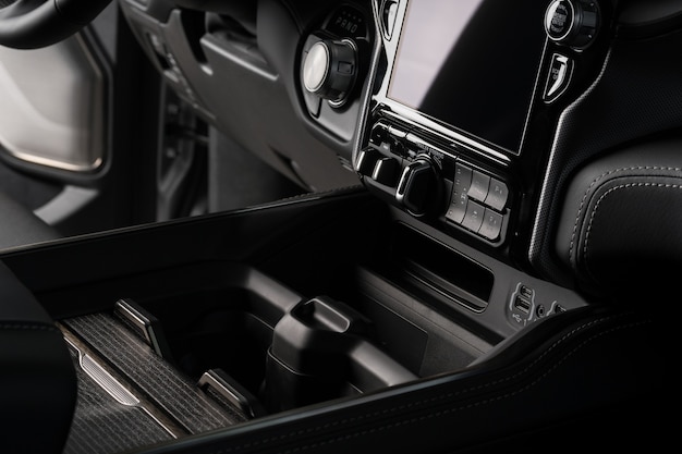 Cup holder close up inside a black luxury car, touch screen system display