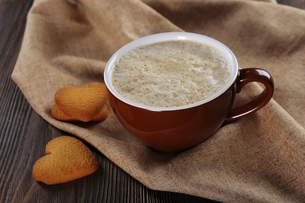 Cup of hot cacao with heart shaped cookies on cotton serviette close up