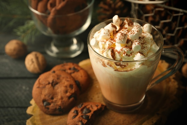 Cup of hot cacao with marshmallow and cookies on black table