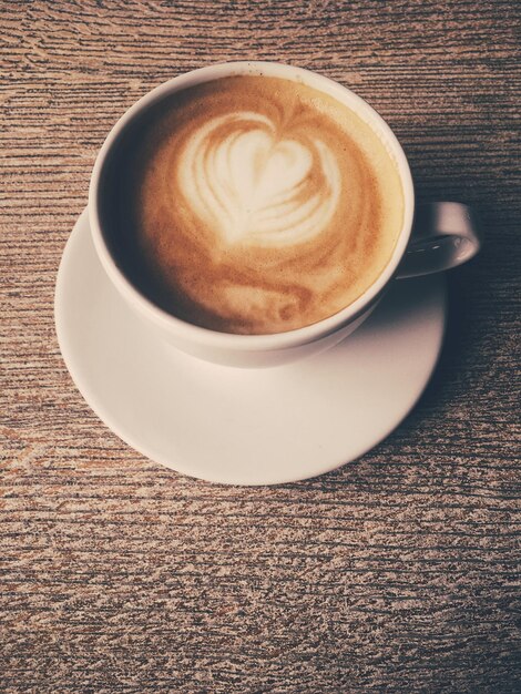 Cup of hot cappuccino in a cafeteria coffee on a wooden table in cafe