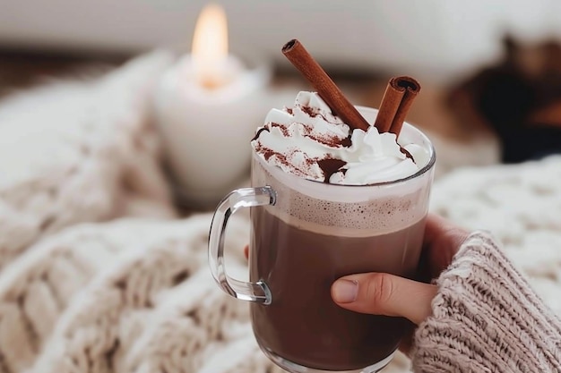 Photo a cup of hot chocolate with cinnamon sticks in it and a candle in the background