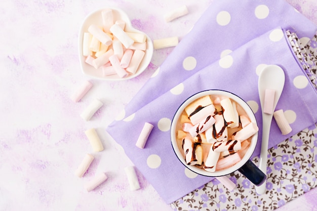 Cup of hot cocoa or chocolate with marshmallow on a light table.