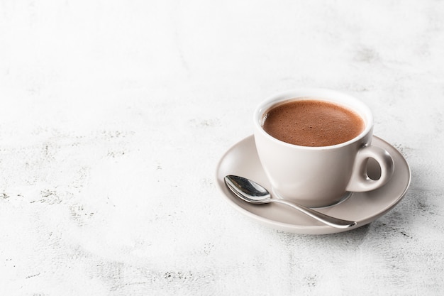 Cup of hot cocoa or hot chocolate or americano in white cup isolated on bright marble background. Overhead view, copy space. Advertising for cafe menu. Coffee shop menu. Vertical photo. traditional