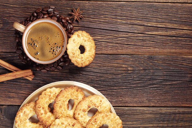 Cup of hot coffee and cookies wits nuts on dark wooden table