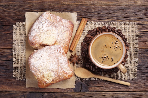 Photo cup of hot coffee and two fresh buns on dark wooden table. top view