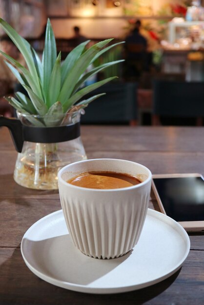 Cup of Hot Coffee with Potted Marble Queen Plants and Mobile Phone in Background