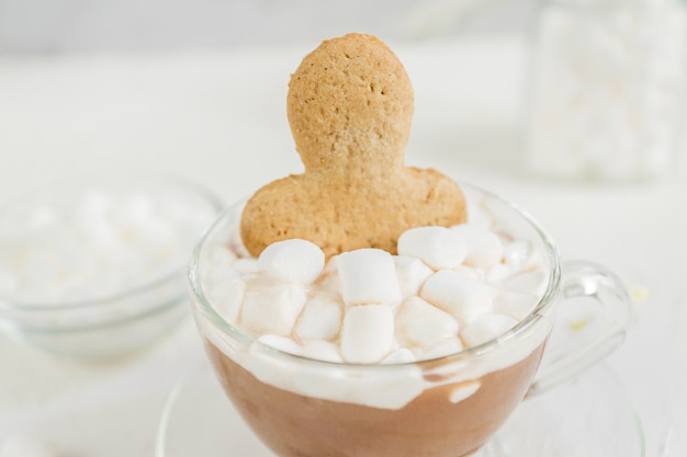 Cup of hot delicious cocoa drink with marshmallows and ginger man.