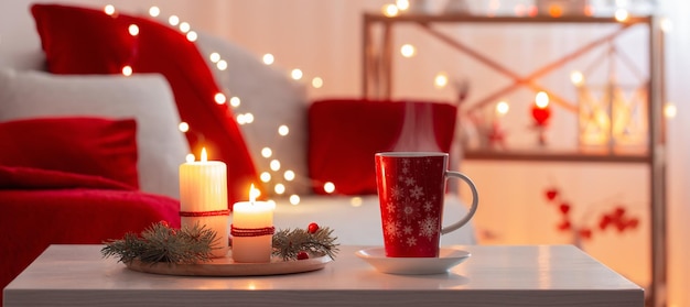 Cup of hot drink with christmas decorations in white and red colors at home