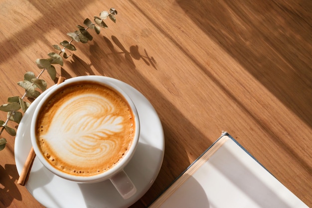 A Cup of hot latte art coffee on wooden table with book in coffee shop cafe.