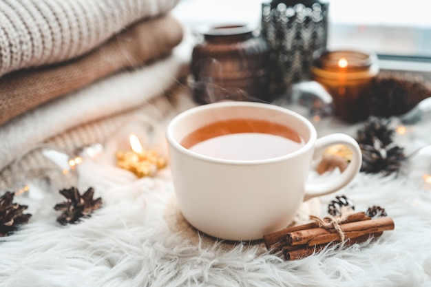 A cup of hot tea and a stack of knitted sweaters on the windowsill aesthetic photo