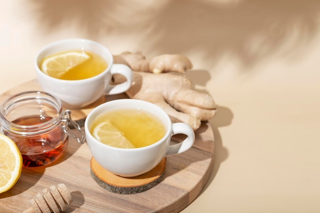 Cup of hot tea with ginger honey and lemon on the beige background copy space for text